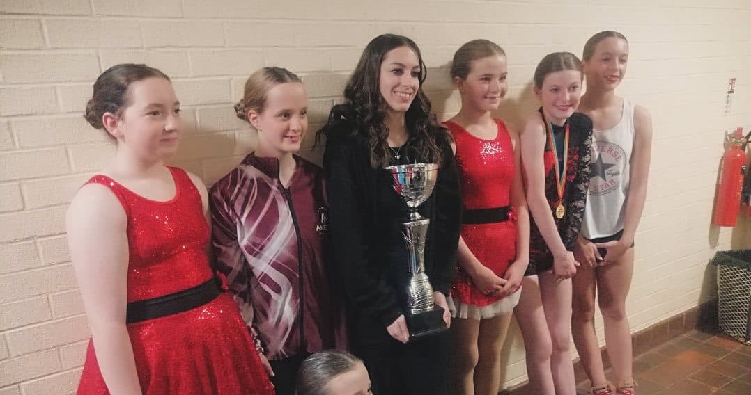A festival trio holding trophies on the podium