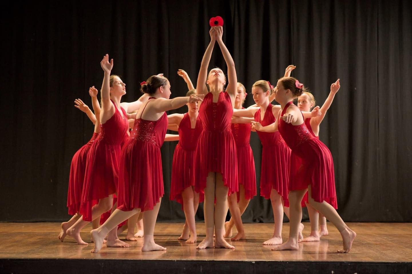 Red ensemble mid leap, hosted by West End summer school choreographers