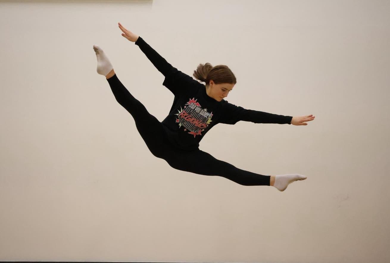 A soloist performing a grand jeté on stage