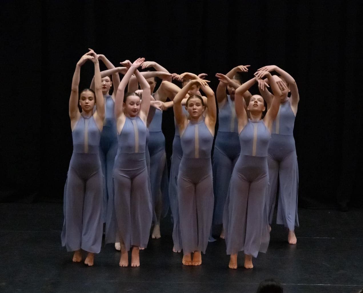 Ensemble in teal costumes holding a formation