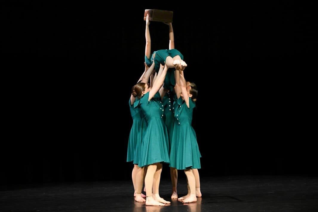 Ensemble performing a lift in teal costumes