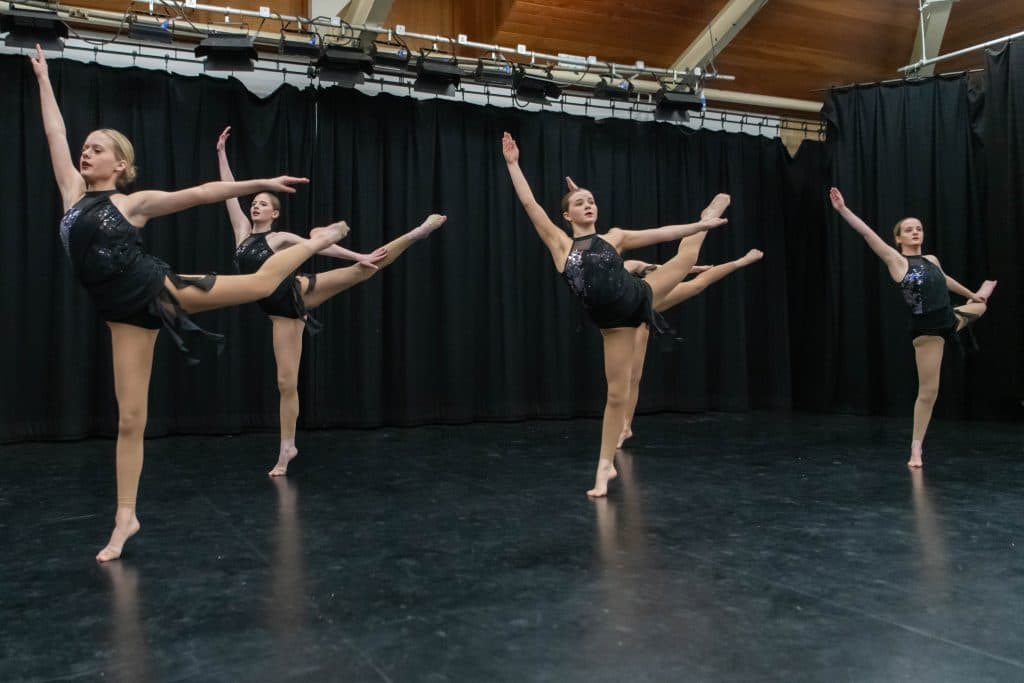Trio performing a unison leap on stage